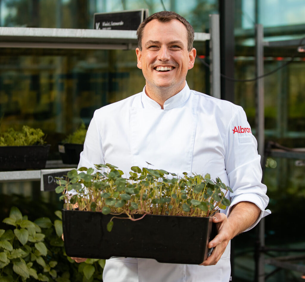 Chef kok met verse kruiden uit groentekas en kruidenkas in het restaurant