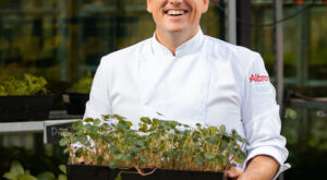 Chef kok met verse kruiden uit groentekas en kruidenkas in het restaurant